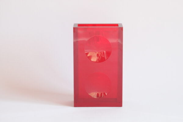A vintage red acrylic vase in a rectangular shape with a round imprint on both sides. Designed by Fabio Manlio Ciocca for Guzzini.