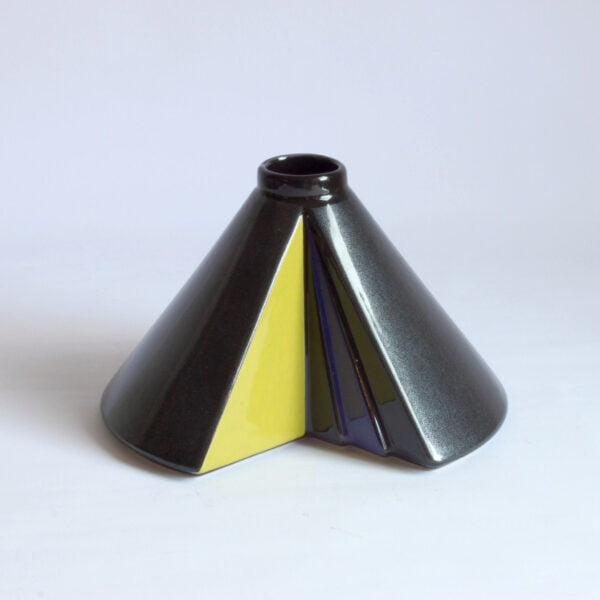 A conical ceramic vase missing a slice, designed by Steuler Keramik (1917 – 1996). Shaped like a cone with a slice taken out to create a hollow inside which has been decorated in yellow, blue and black triangles. The outer glaze which seems black or dark grey from far away, reveals a very postmodern Memphis-group like bacteria shaped glossy finish when you look closer. Century soup vintage design antiques curiosa collectibles antwerp.