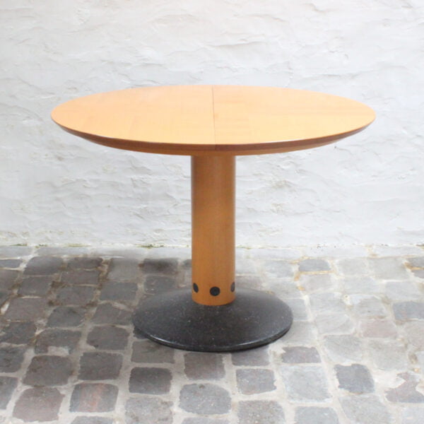 Postmodern round extendable dining table "Diabolo" by Arnold Merckx for Arco, The Netherlands 1980s. Granite base with granite inlaid wooden pedestal pillar. The table is 105cm diameter. It can be extended to 157cm X 105cm with a 52cm panel.