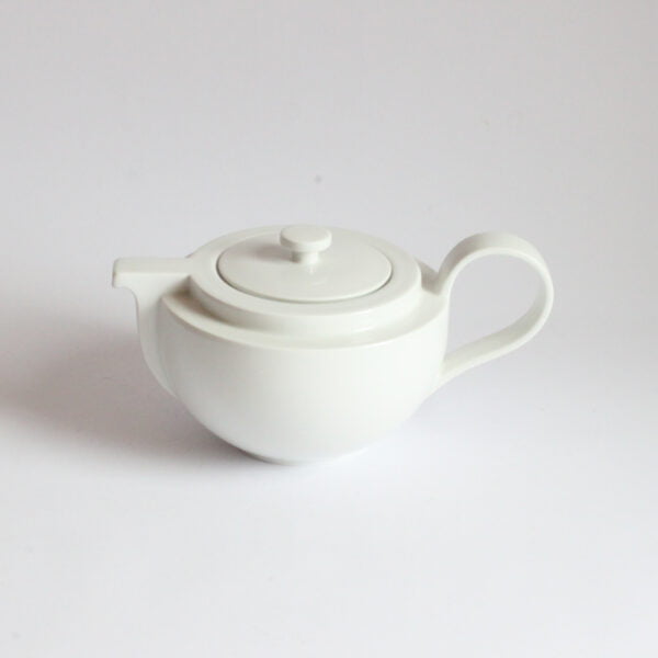 White porcelain teapot with a ledge near te top, the spout looks like the bow of a boat and follows down. The bottom half is rounded. Cult teapot by Dieter Sieger for Arzberg.