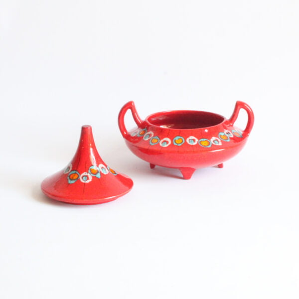 Red ceramic bonbonnière or biscuit box with a pointy "hat shaped" lid and devil horn shaped handles. Lid on the side.