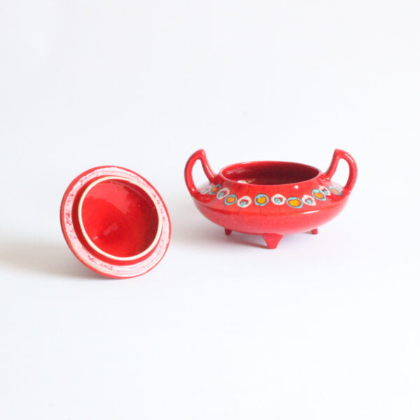 Red ceramic bonbonnière or biscuit box with a pointy "hat shaped" lid and devil horn shaped handles. Lid underneath.