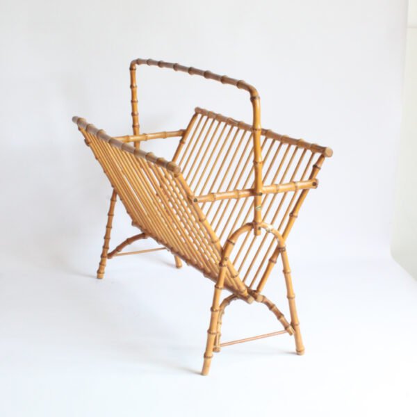 A 1950s magazine rack or newspaper stand made entirely from bent bamboo. The outer frame is made from the thicker parts with the knots. And the sides are made from thinner, more smooth bamboo sticks. Typical 1950s boomerang shaped legs.