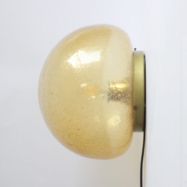 A bubble glas or "Pulegoso" technique wall or ceiling lamp by Glashütte Limburg, Germany 1970s. The shade is blown in a mushroom shape, and sits on a round brass base. The bulb is held inside on a reclining brass cone.
