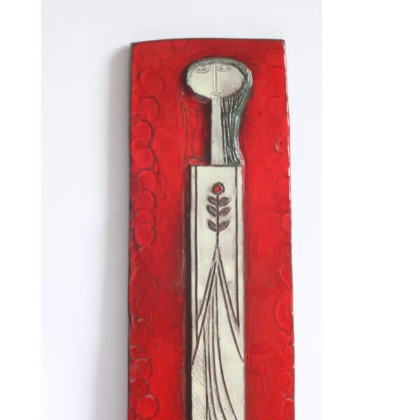 Tall square ceramic wall ornament with a red glaze by Oswald Tieberghien. Depicting a stylized elongated woman in a white dress holding a flower.