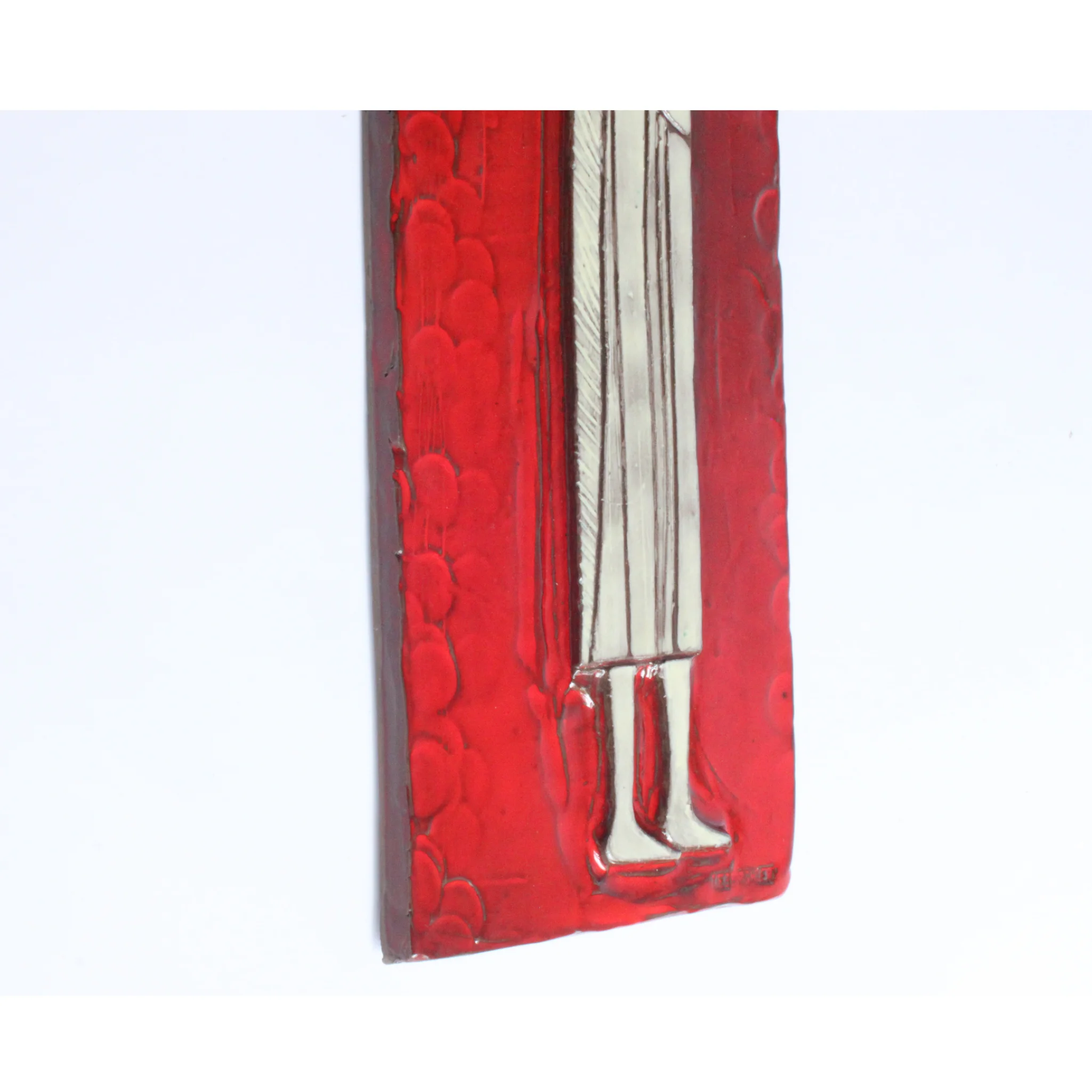 Tall square ceramic wall ornament with a red glaze by Oswald Tieberghien. Depicting a stylized elongated woman in a white dress holding a flower.