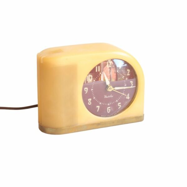 A vintage design alarm clock in yellow bakelite,"Moonbeam" by Westclox Peru, Illinois USA. Designed in 1949 in a streamline art deco style. Bakelite body and brass base. Century Soup vintage design collectibles antwerp.