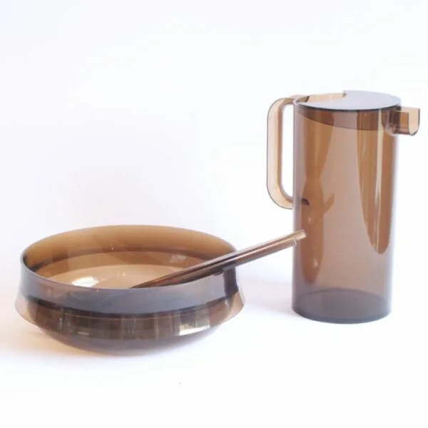 Guzzini per alimenti salad bowl, salad spoon and fork, and a pitcher in smoked lucite or acryl. A salad bowl or serving bowl with a very 1970s space age style rim (like Darth Vaders helmet), with a matching set of serving utensils. The pitcher had an opening in the lid so that the spoon can be used as a stirring tool. Both with the original Guzzini label, one with an additional label of the Belgium based design store that sold Italian design in the seventies | Century Soup |