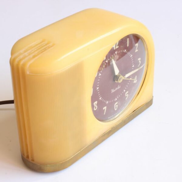 A vintage design alarm clock in yellow bakelite,"Moonbeam" by Westclox Peru, Illinois USA. Designed in 1949 in a streamline art deco style. Bakelite body and brass base. Century Soup vintage design collectibles antwerp.