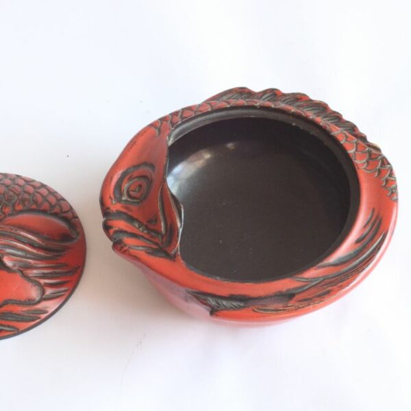An early 20th Century red Takaoka Lacquerware Kashibako lidded bonbonniere, confectionery box or sweets jar in the shape of a Sea Bream fish. The sap is harvested from the Urushi tree. Shikki is also often referred to as “nurimono”, or painted things. Typically lacquer is applied to a wooden core with multiple layers of coating. There are a number of techniques of application and decoration. Takaoka Shikki exists over 400 years. Tradition has it that Takaoka- shikki lacquerware was first produced when Oba Shozaemon, who moved to the castle town, coated the furniture he made with lacquer. This was followed by wardrobes and nagamochi (large oblong chests for storing garments and household goods) and eventually tableware, kitchen utensils and other items for everyday use. Takaoka lacquerware offers a wide range of reliable products backed by tradition, and was designated a traditional craft in 1975. Century Soup vintage design antiques collectibles and curiosa antwerp.