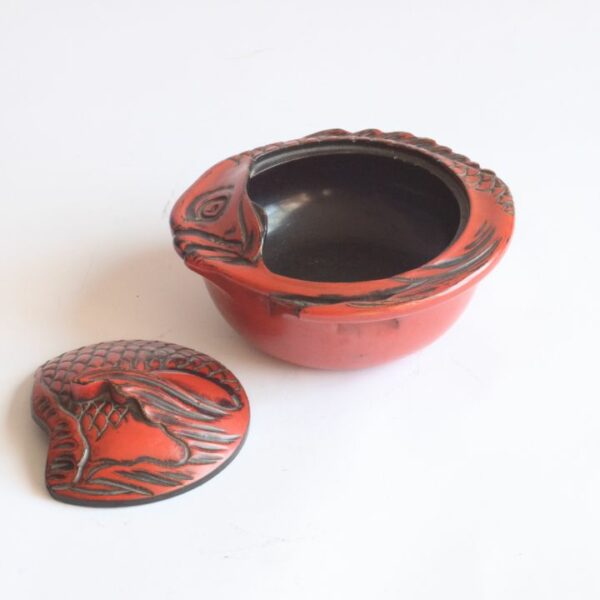 An early 20th Century red Takaoka Lacquerware Kashibako lidded bonbonniere, confectionery box or sweets jar in the shape of a Sea Bream fish. The sap is harvested from the Urushi tree. Shikki is also often referred to as “nurimono”, or painted things. Typically lacquer is applied to a wooden core with multiple layers of coating. There are a number of techniques of application and decoration. Takaoka Shikki exists over 400 years. Tradition has it that Takaoka- shikki lacquerware was first produced when Oba Shozaemon, who moved to the castle town, coated the furniture he made with lacquer. This was followed by wardrobes and nagamochi (large oblong chests for storing garments and household goods) and eventually tableware, kitchen utensils and other items for everyday use. Takaoka lacquerware offers a wide range of reliable products backed by tradition, and was designated a traditional craft in 1975. Century Soup vintage design antiques collectibles and curiosa antwerp.