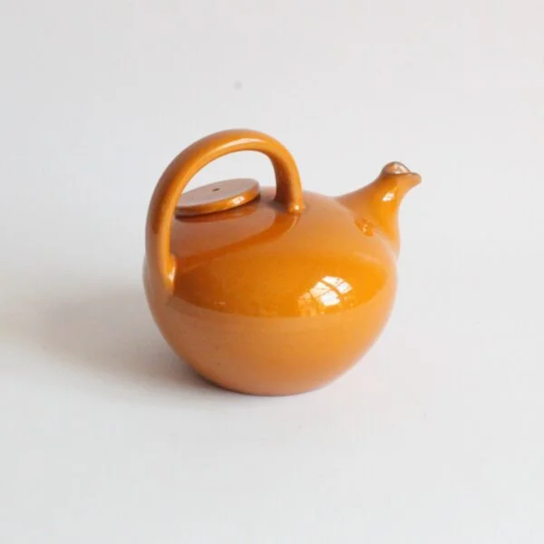 A vintage artisanal Scandinavian modern style pottery teapot in a beige color. Rounded body with a large handle and the lid on the left side. The Ildfast collection was produced from 1941 till the 1960s. Marked underneat: BS for Brack and Sønner Denmark Century soup vintage design antiques curiosa collectibles antwerp.