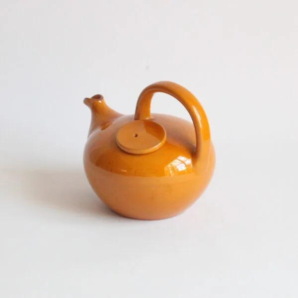 A vintage artisanal Scandinavian modern style pottery teapot in a beige color. Rounded body with a large handle and the lid on the left side. The Ildfast collection was produced from 1941 till the 1960s. Marked underneat: BS for Brack and Sønner Denmark Century soup vintage design antiques curiosa collectibles antwerp.